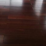 Habitación con suelo de Piso de Madera Granadillo Rojo pulido, grandes ventanales y vistas a la vegetación y a los edificios de la ciudad en el exterior.