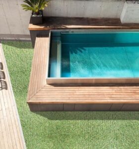 Deck elevado de Pasto Sintético con piscina rectangular integrada y área de césped adyacente.