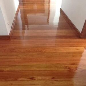 Piso de madera pulida de pasillo con marcos de puertas marrones; el texto en la parte inferior derecha dice "Piso de Madera Granadillo Miel.