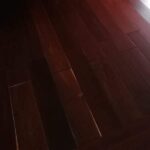 Habitación con suelo de Piso de Madera Granadillo Rojo, estanterías vacías, gran puerta corredera de cristal y vista parcial al patio exterior.