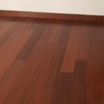 Habitación vacía con suelo de Piso de Madera Incienso, paredes blancas, zócalos marrones y enchufes visibles.