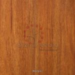 Superficie de madera con la marca "Piso Laminado Nogal" y una incrustación decorativa que muestra un pequeño árbol con hojas rojas y la palabra "nogal" en la parte inferior.