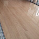 Una habitación con suelos de Piso de Madera Guaimaro, una cenefa de azulejos decorativos, un gran espejo y dos personas en un rincón junto a un perro.