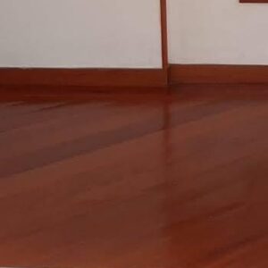 Vista interior de una habitación vacía con suelos de Piso de Madera Incienso, una escalera con peldaños de madera y barandilla metálica, y una puerta abierta que conduce a la cocina.