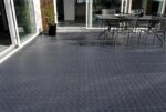Área de patio exterior con piso de Piso de Polipropileno XL y muebles metálicos.