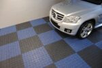 Un auto plateado estacionado en un Piso de Polipropileno XL con azulejos azules y negros.