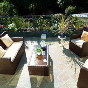 Patio exterior con muebles de Piso de Polipropileno Único y plantas decorativas en un soleado jardín.
