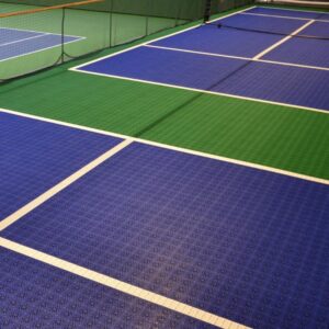 Canchas de tenis cubiertas con superficies de Piso de Polipropileno Tenis azules y verdes y líneas blancas visibles que marcan los límites.