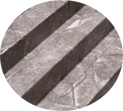 Una imagen en escala de grises de lo que parece ser un conjunto de tres escalones hechos de piedra o mármol con texturas y grietas prominentes.
