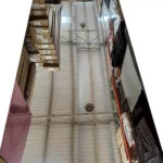 Vista interior de un almacén alto con hileras de cajas y palés apilados que llegan hasta el techo alto.