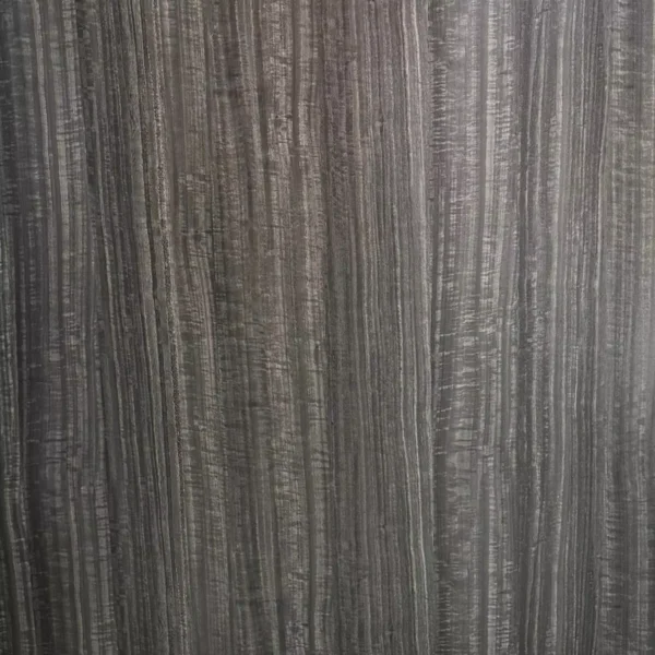 Primer plano de una superficie texturizada de Lámina PVC para paredes de color gris oscuro con patrones de vetas verticales.