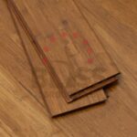 Tres tablas de suelo de bambú apiladas una sobre otra, expuestas sobre una superficie de suelo de bambú a juego.